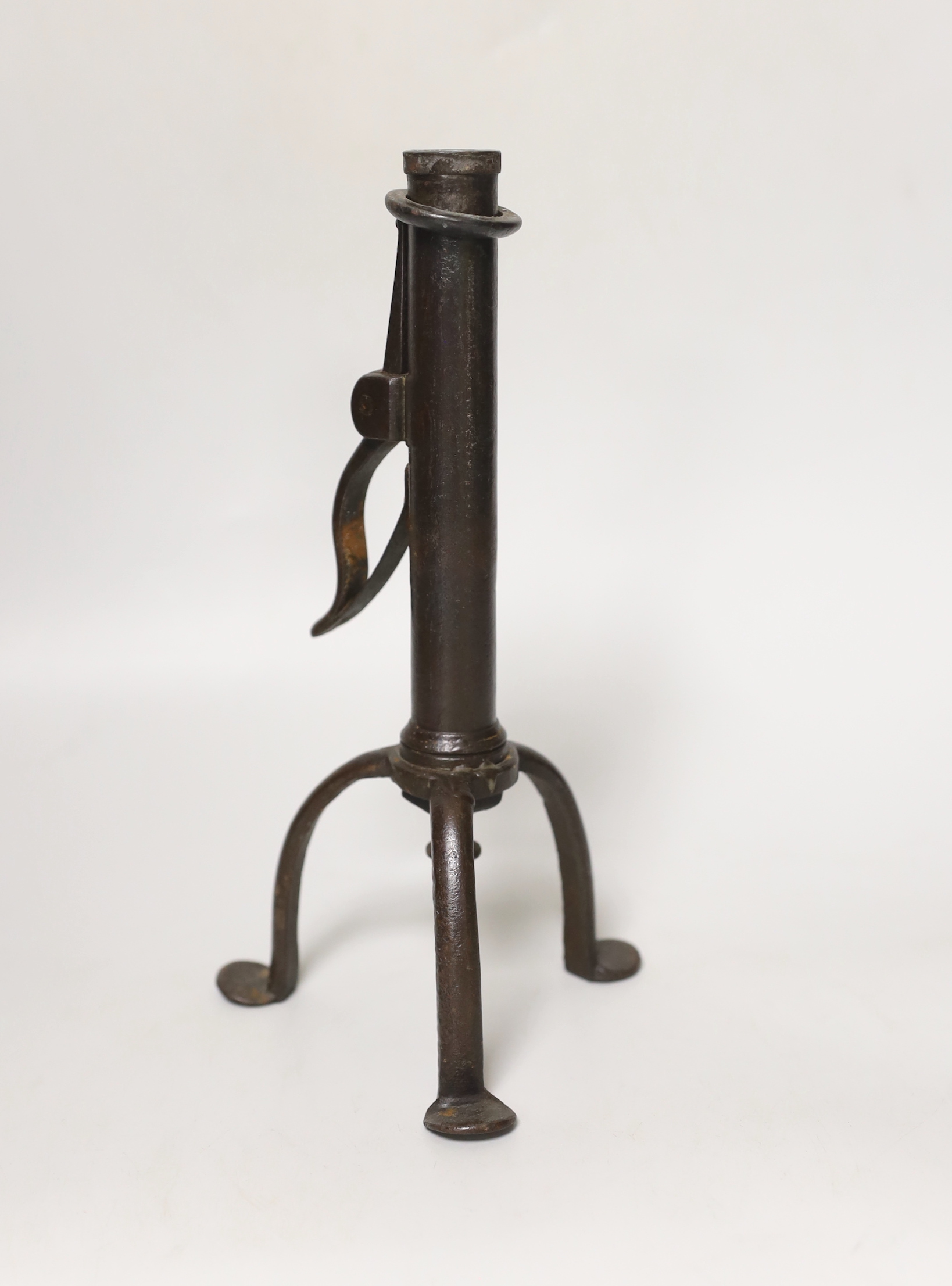 An 18th century rare iron candle holder, English, on tripod base, the cylindrical stem with push ejector with side spring rushlight nip, 22.5cm tall